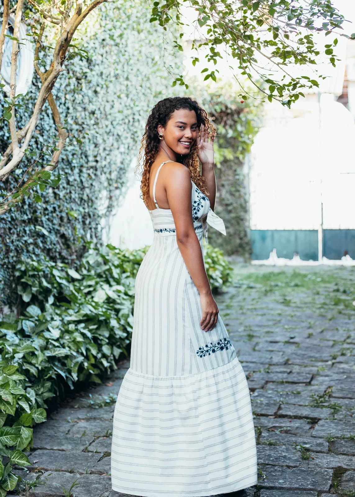 Woman wearing a white summer dress in a leafy garden